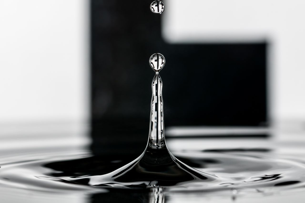 Stunning black and white image of a water drop captured mid-splash, showcasing mesmerizing detail and precision.