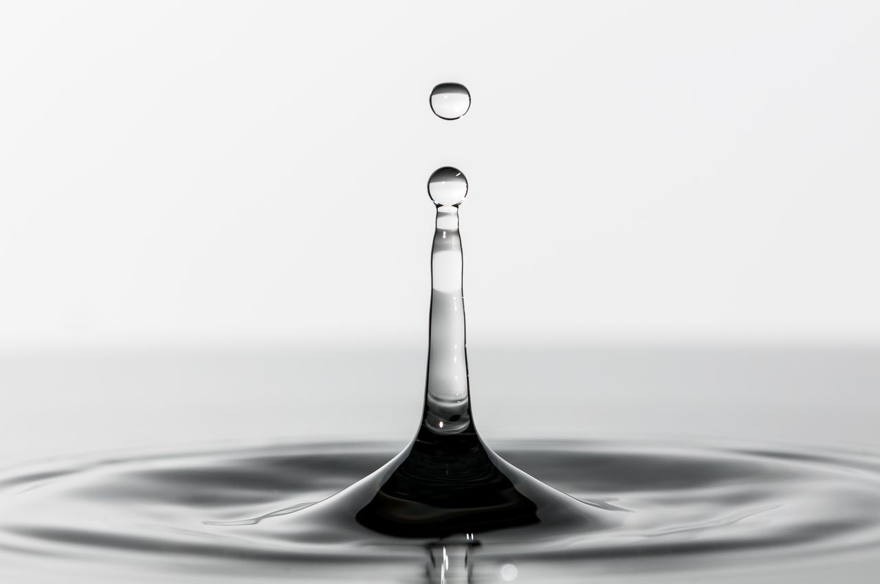 High-resolution macro shot of a single water droplet on a serene surface, showcasing detail and clarity.