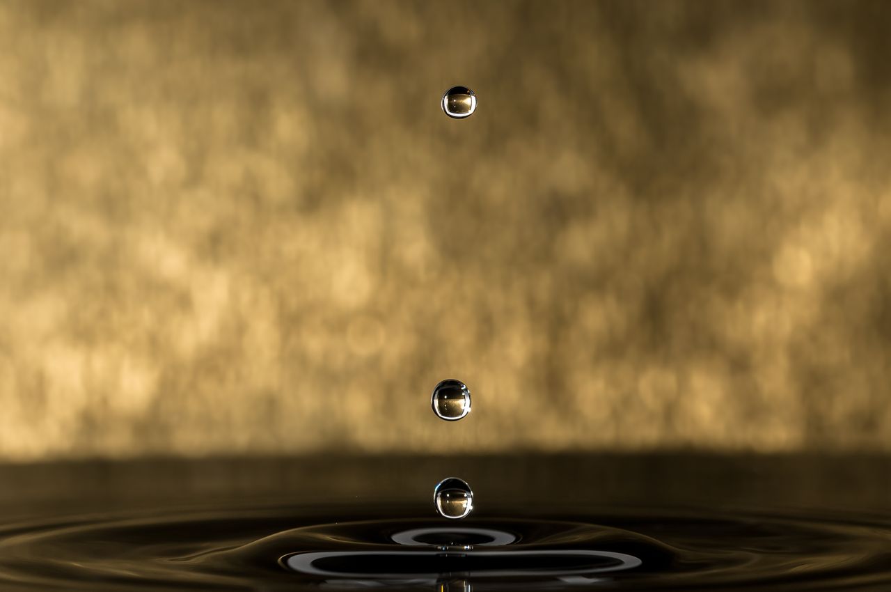 Artistic macro shot of water droplets against a gold background showcasing reflection and intricate detail.