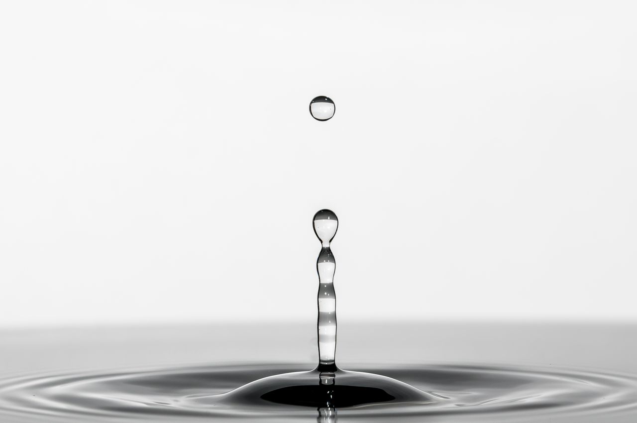 A striking black and white macro photograph capturing a water droplet's elegant motion and reflection.
