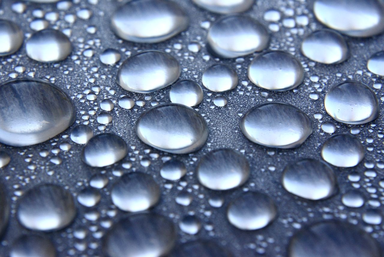 Sharp and detailed image of water droplets on a smooth surface, showcasing surface tension.