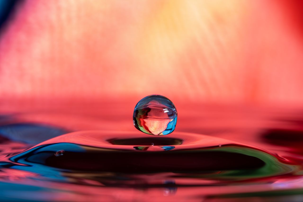 Macro shot of a water drop creating colorful reflections and refractions, captured in high speed.
