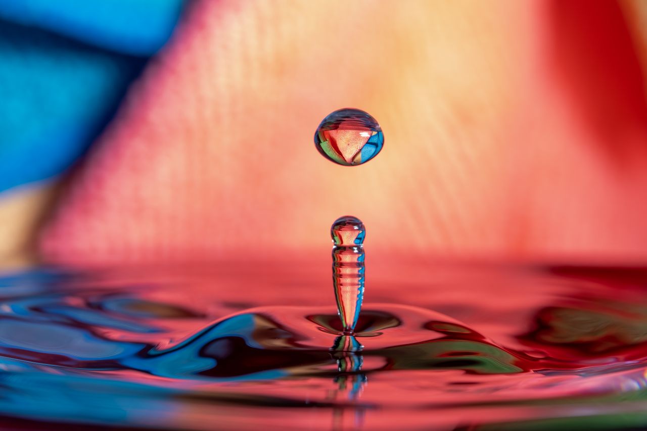 Colorful high-speed photograph of a water drop splash with vibrant reflections and refractions.